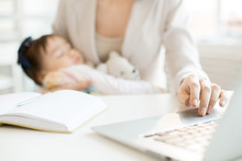 Hand Of Business Mother On Laptop Keypad During Network In Office With Sleeping Baby In The Other One