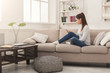 © Prostock-studio - Young girl using mobile phone on sofa
