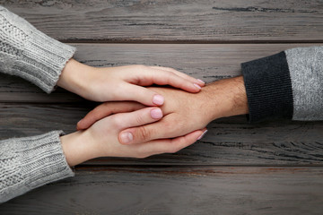 Wall Mural - Female and male hand holding each other on grey background