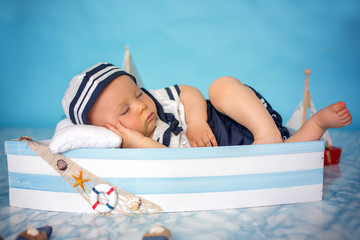 Sticker - Cute toddler baby boy sleeping in wooden boat with fishes, starfish and binoculars, dressed as sailman