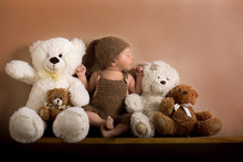 Newborn Baby Boy Wearing A Brown Knitted Bear Hat And Pants, Sleeping On A Shelf