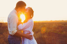 Young Beautiful Couple Kissing Against Sunset Rays Outdoor In Field On Sunset