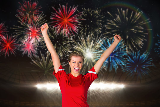 Cheering football fan in red against fireworks exploding over football stadium