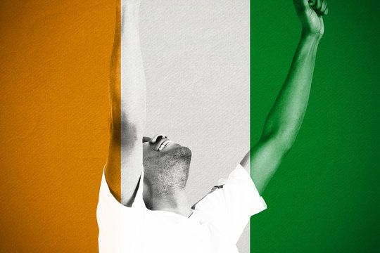 Excited handsome football fan cheering against ivory coast national flag