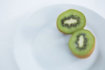 Wall Mural - Halved kiwis in plate on white background