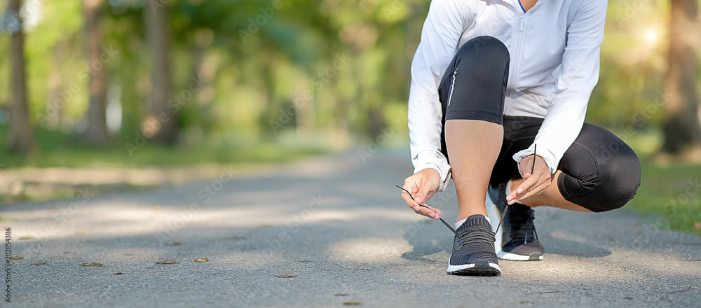 young fitness woman legs walking in the park outdoor, female runner running on the road outside, asian athlete jogging and exercise on footpath in sunlight morning. Sport,healthy and wellness concepts - obrazy, fototapety, plakaty 
