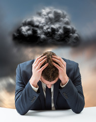Poster - Businessman with head in hands against blue and orange sky with clouds