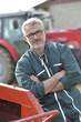 © goodluz - Farmer standing by tractor outside the barn
