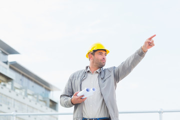Poster - Architect with blueprints pointing towards sky