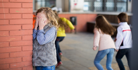 playing hide and seek.  Girl covering eyes her hands standing at brick wall