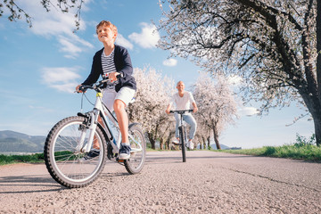 Father and son have a fun active leisure together - ride bicycles on country road