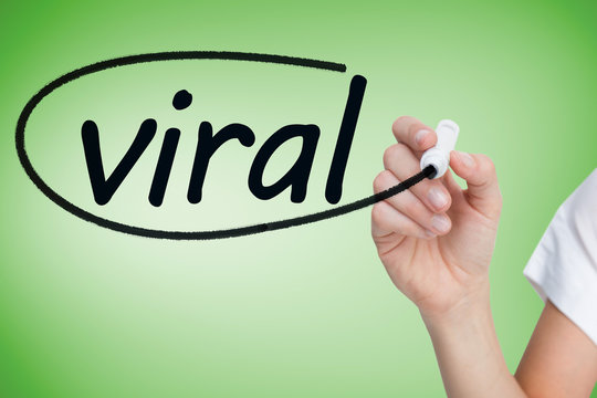 Businesswoman writing the word viral against green vignette