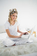 © WavebreakmediaMicro - Cheerful cute blonde wearing hair curlers using laptop