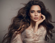 © Victoria Andreas - Beauty fashion brunette portrait. Sexy woman wears in stylish fur coat. Beautiful girl model with evening makeup, long healthy curly hair style posing over studio gray background.