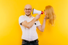 Odd Unusual Couple Of Lovers. Crazy Foolish Strange Man With Beautiful Women Head. Baldness And Hairy People Concept. Odd Stylish Fashionable Guy In Glasses With Girlfriend Have Fun On Yellow Wall.