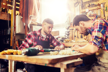 profession, carpentry, woodwork and people concept - two carpenters with ruler and blueprint at workshop