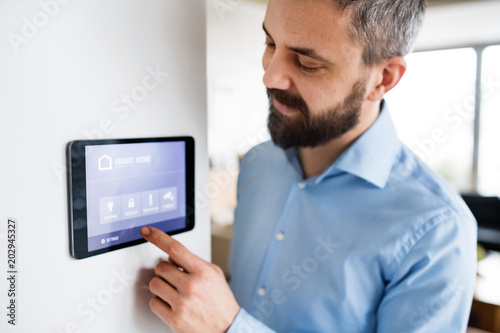 Cuadros en Lienzo A man pointing to a tablet with smart home screen at home.