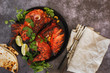 Indian tandoori chicken with naan, lime slices and cilantro, ready to eat. Top view, blank space