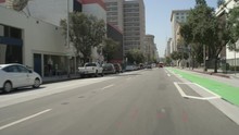 Front View Of A Driving Plate: Car Turns Right From West 2nd Street In Los Angeles, California Onto South Spring Street And Continues Past A Group Of Protesters To The Intersection Of West 4th Street.