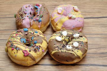 Wall Mural - Decorated doughnuts on a wooden background