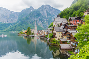 Wall Mural - Scenic picture-postcard view of famous Hallstatt mountain village in the Austrian Alps with passenger ship in beautiful morning light at sunrise on a sunny day in summer, Salzkammergut region, Austria