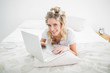 © WavebreakmediaMicro - Cheerful blonde wearing hair curlers using laptop