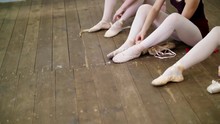 Close Up, Ballerinas Change Their Shoes Into Special Ballet Shoes, Pointe Shoes, Lace With Ballet Ribbons, On An Old Wooden Floor, In Ballet Class.
