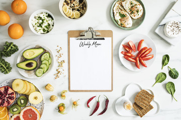 Mock up for weekly menu. Variety of vegetables, fruits and seeds on the kitchen marble table. New healthy lifestyle.