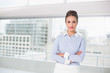 © WavebreakmediaMicro - Content brunette businesswoman standing with arms crossed