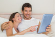 © WavebreakmediaMicro - Happy couple using digital tablet in bed