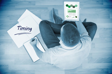Poster - The word timing and business graphs against young creative businessman looking at tablet