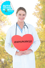 Poster - The word awereness and doctor holding red heart card  against autumnal leaves against the clear sky