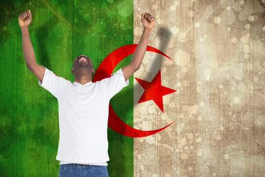 Excited handsome football fan cheering against algeria flag in grunge effect