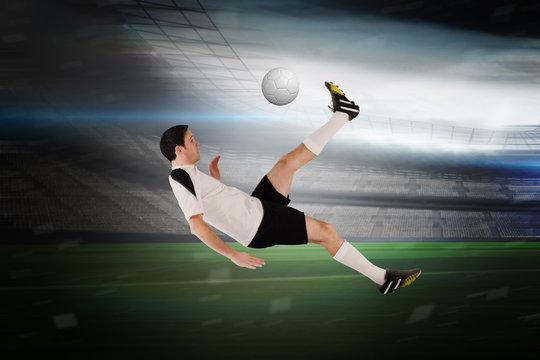 Football player in white kicking in a large football stadium with lights