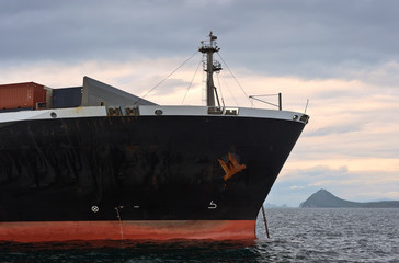 The bow of a huge container ship at anchored in the roads.