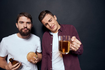 men on a dark background, beer and hamburgers in hands