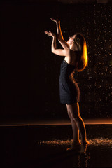 Wall Mural - Girl in black dress in water in a small pool, drops of water and dark background