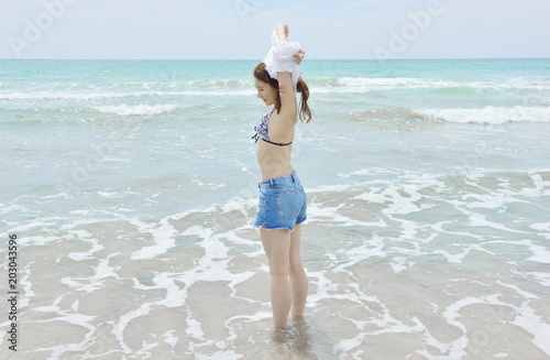 波打ち際でtシャツを脱ぐ女性 Stock 写真 Adobe Stock 波打ち際でtシャツを脱ぐ女性 Stock 写真 Adobe Stock