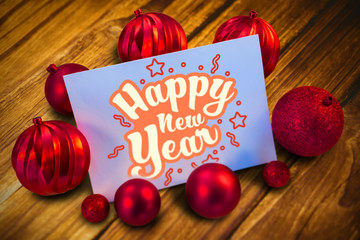 Leinwandbilder - Red christmas baubles surrounding white page against bleached wooden planks background