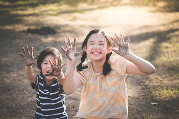 Asian children playing outside with dirty hands