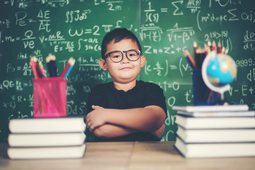 Wall Mural - Thoughtful little boy with book near a school board