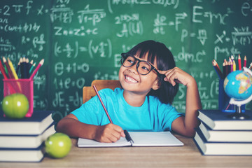 Wall Mural - Thoughtful little girl with book near a school board