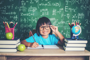 Wall Mural - Thoughtful little girl with book near a school board