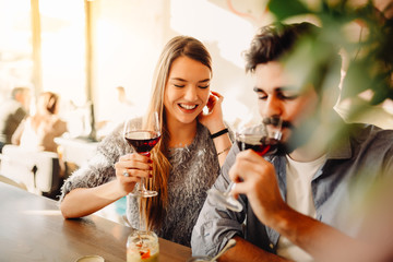 Wall Mural - Blonde girl is drinking wine with her boyfriend in cafe