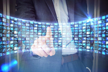 Poster - Businessman in grey suit pointing against curve of digital screens in blue