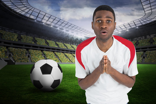 Nervous football fan in white looking ahead against large football stadium with fans in yellow