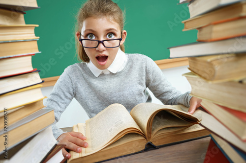 Schoolgirl with open mouth look at camera. Photo of little girl sitting ...