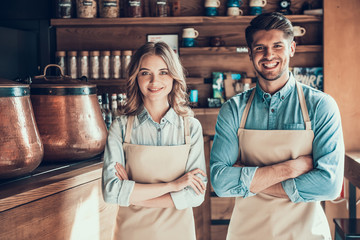 Portrait of two baristas in aprons in coffee shop.