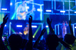 © Voy_ager - Crowd of hands up concert stage lights enjoying concert, and people fan audience silhouette raising hands in festival music rear view with spotlight glowing effect, blurred