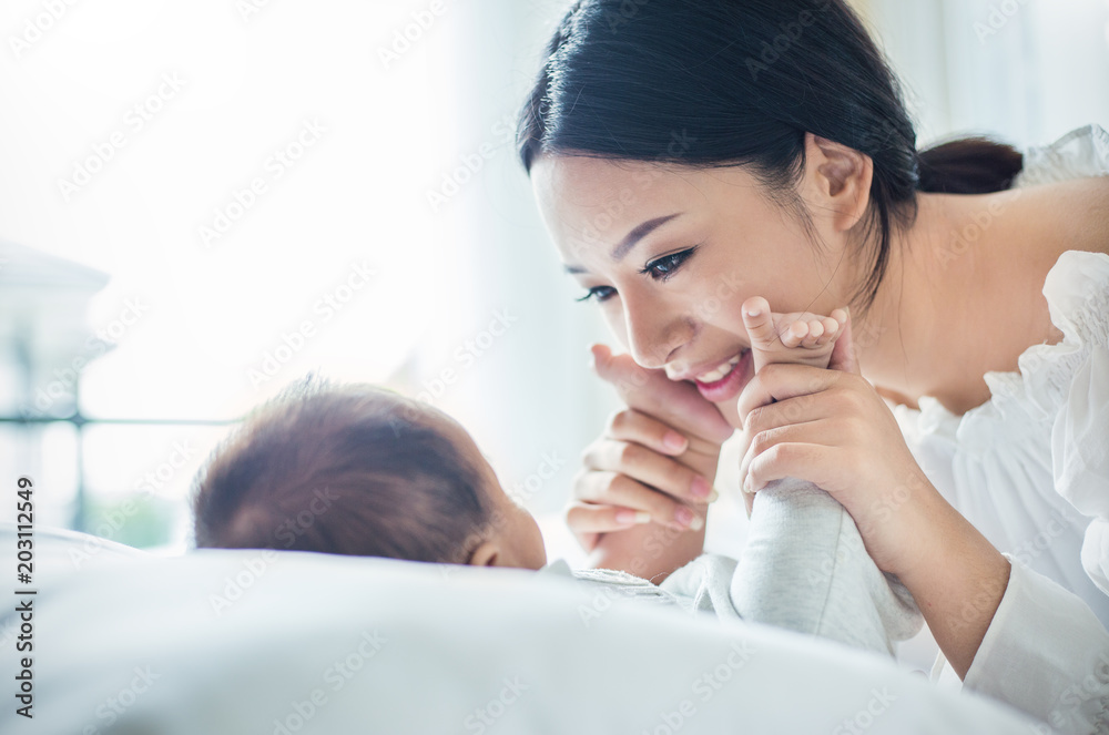 Mother’s hands holding newborn baby feet. Close up portrait of beautiful young asian mother with her newborn baby. Healthcare and medical love lifestyle mother’s day concept - obrazy, fototapety, plakaty 